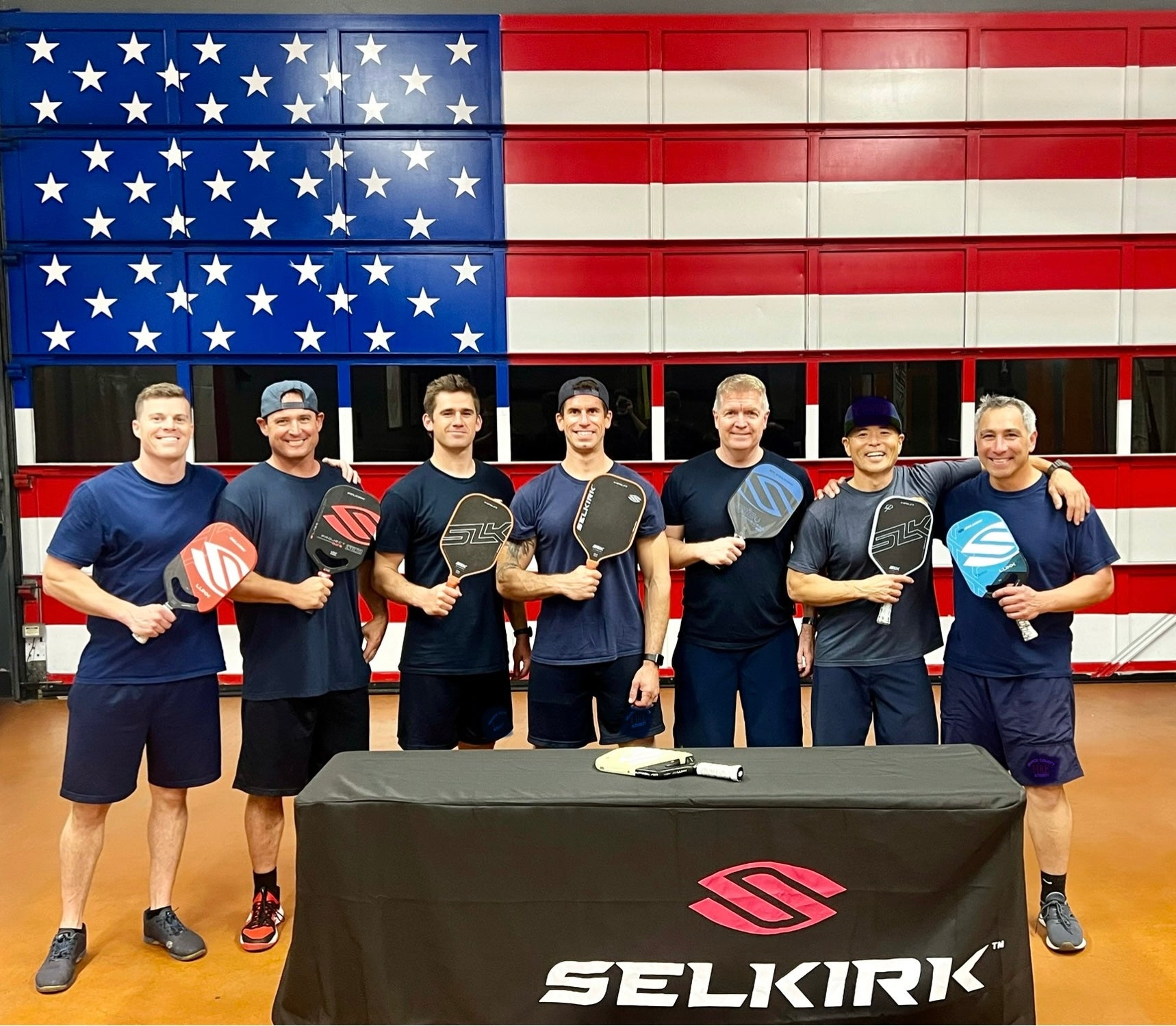 Brian Pingree (second from left) stands in line with his colleagues at the Orange County Fire Authority. They smile at the camera while holding Selkirk pickleball paddles. 