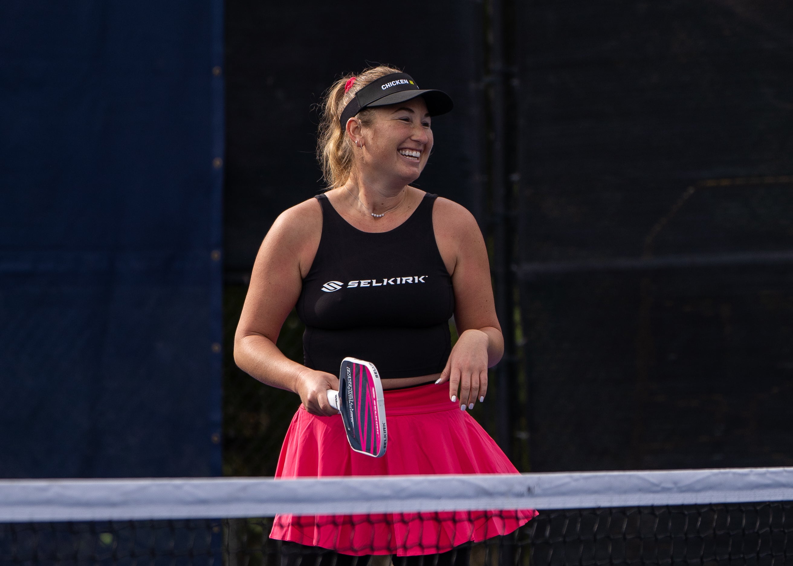 Selkirk Pro Lauren Stratman smiles as she stands on an outdoor pickleball court with her Selkirk Power Air. 