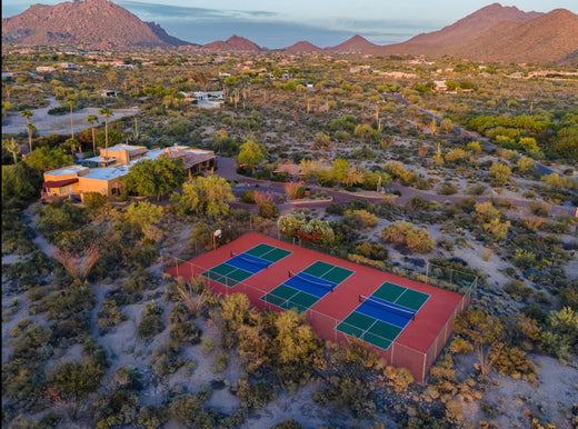 An aerial image shows three pickleball courts nestled below a mountain range in Scottsdale, Arizona. 