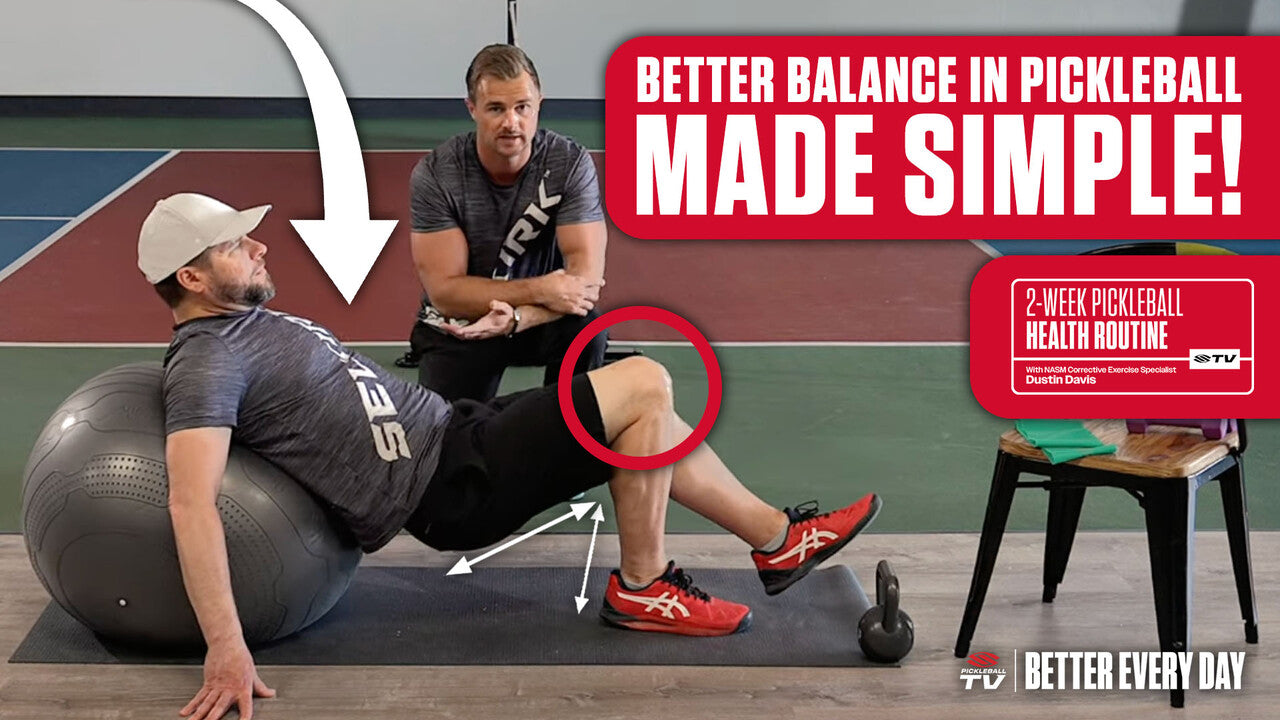 A man performs glute bridges on a yoga ball while a trainer kneels next to him giving him pointers.