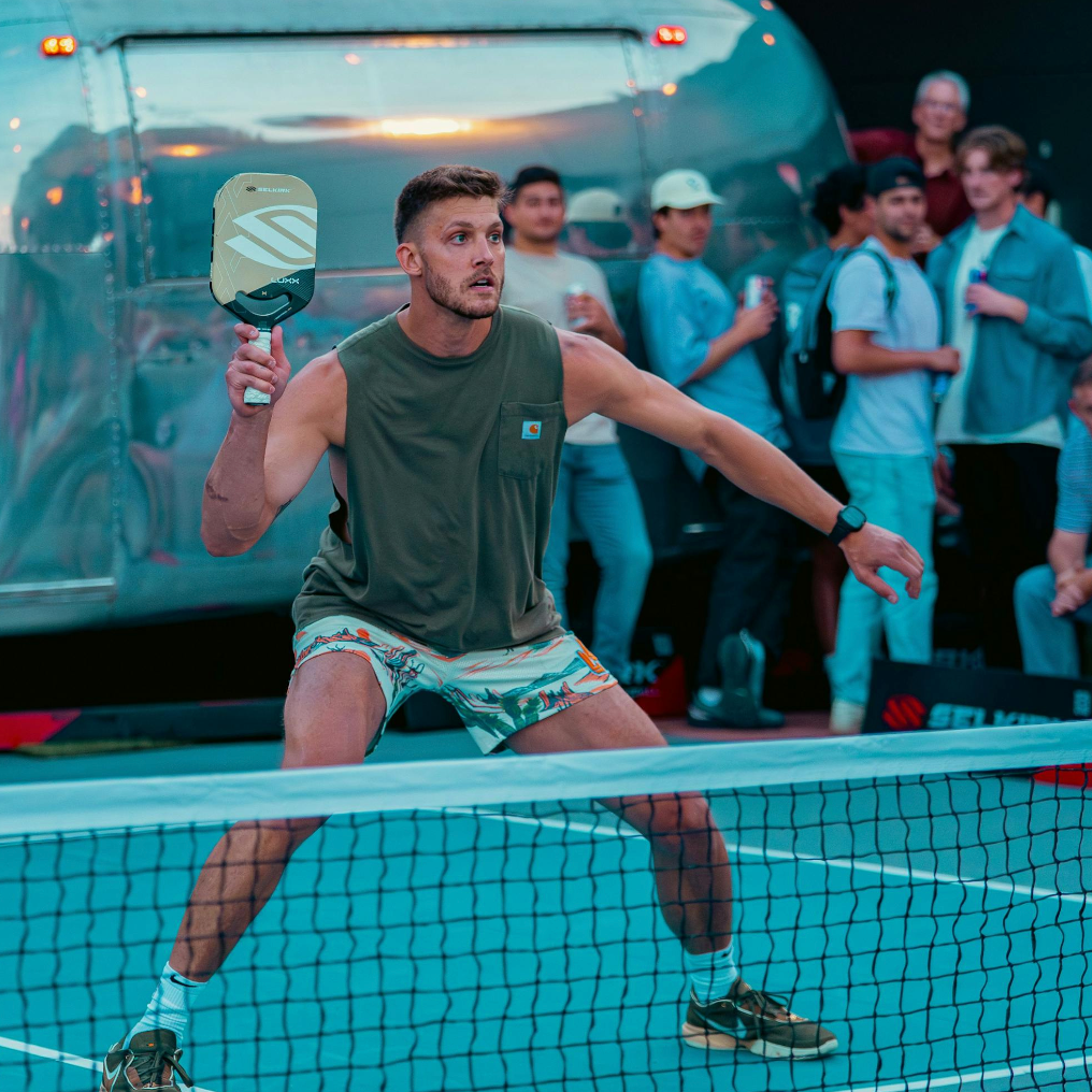 Meyers Leonard uses a Luxx Control Air to hit an overhead volley at the kitchen line of an outdoor pickleball court. 