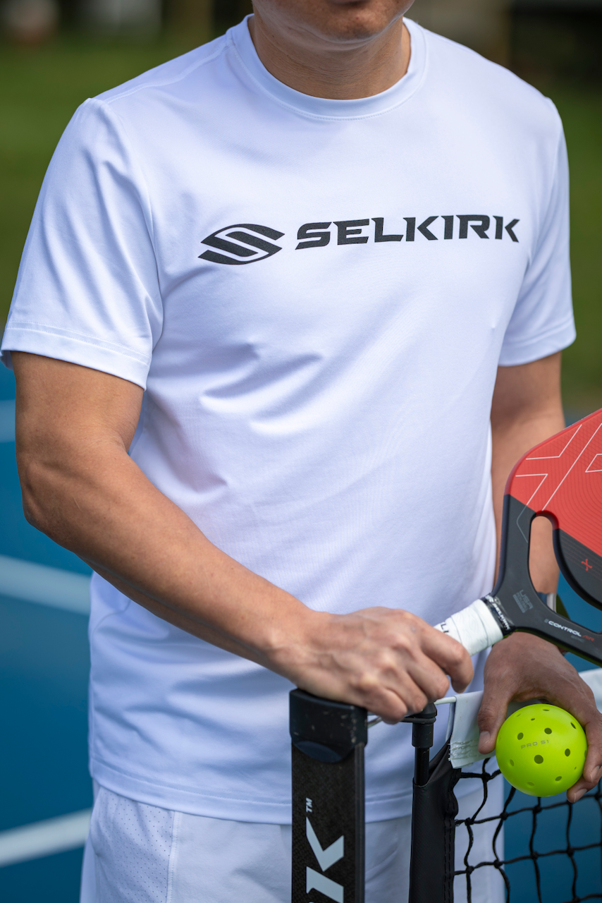 Rhone & Selkirk pickleball collaboration with a white t-shirt with black Selkirk logo and pickleball ball.