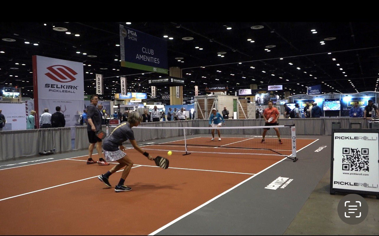 Photo of Selkirk Sport pickleball paddles and balls lying down on a pickleball court.